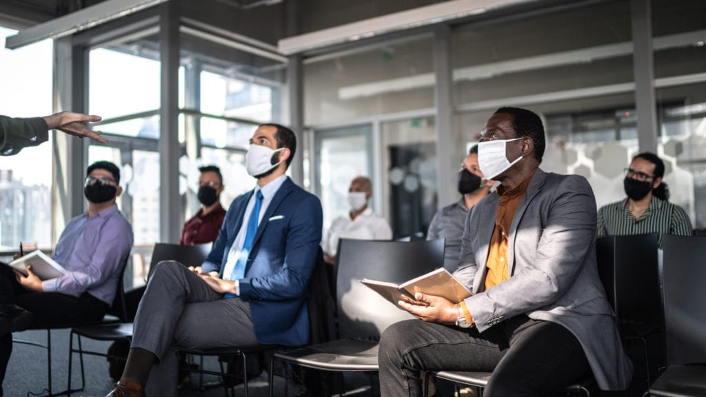 Picture of 7 masked men sitting socially distanced ay a meeting
