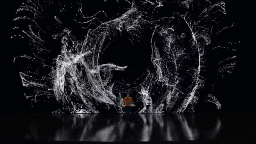 person in yellow shirt stands in front of a gigantic LED screen display