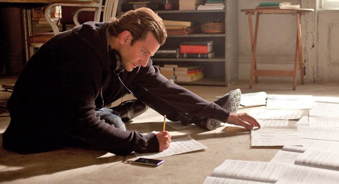 Man working on the floor with paper and pencil. 